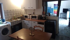 Ett kompakt kök med tvättmaskin, mikrovågsugn, brödrost och kaffebryggare.