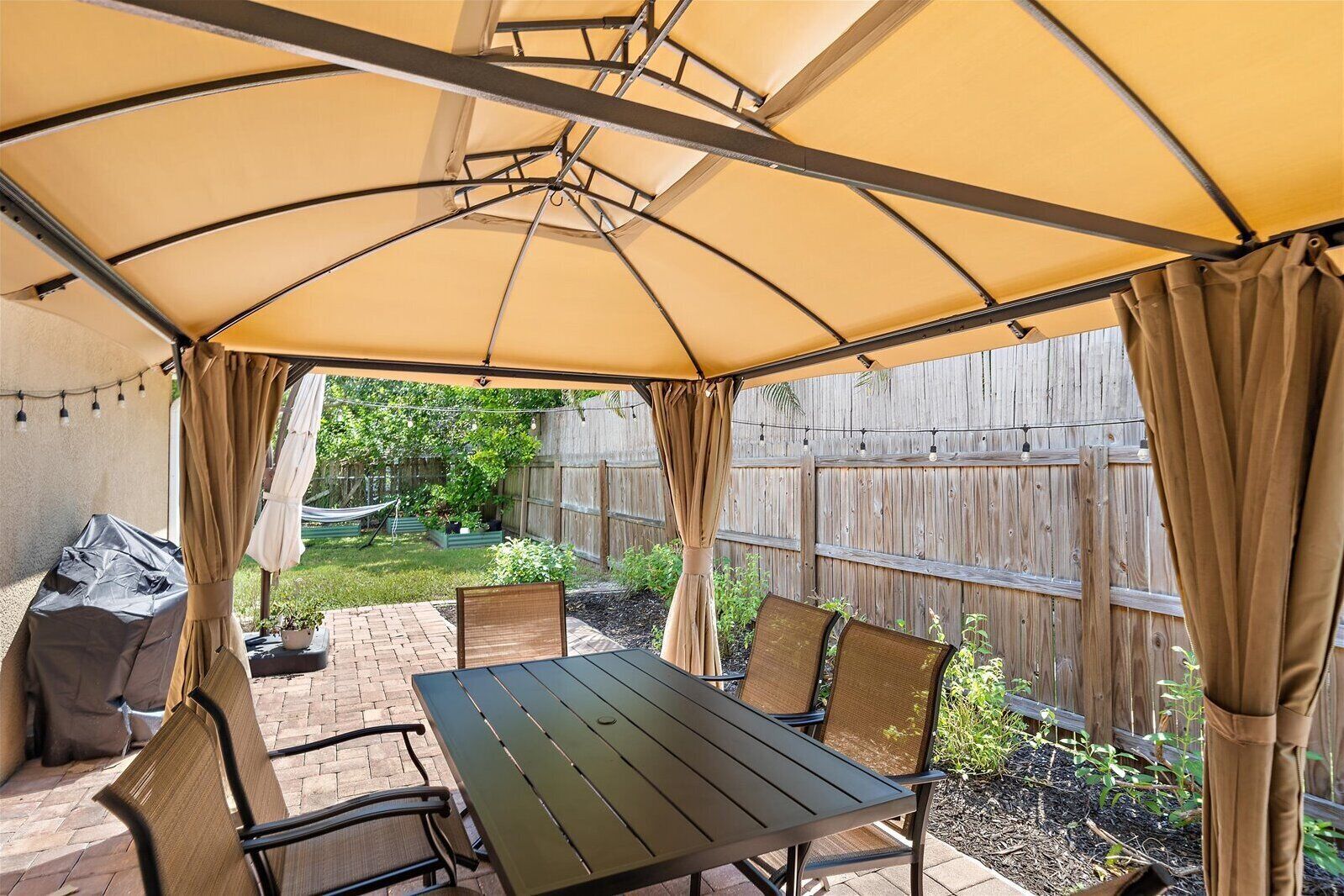 An outdoor patio with a table and chairs under a canopy.