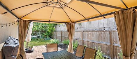 An outdoor patio with a table and chairs under a canopy.