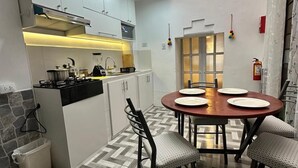 A modern kitchen with a dining area, featuring a herringbone floor pattern, white cabinets, and a central island with a stove. - ZEVEN HOUSE - CUSCO APARTMENT (Cusco)