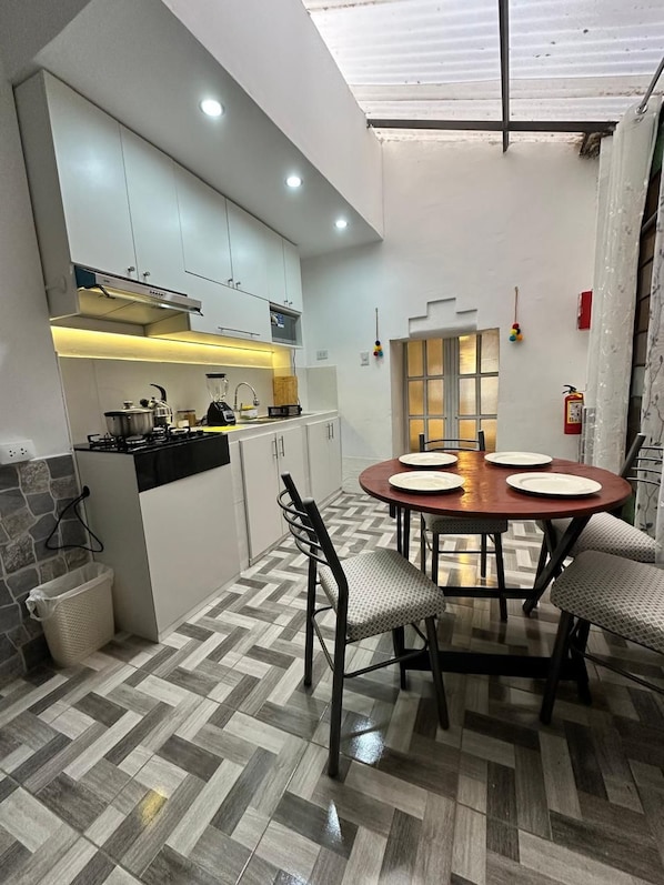 A modern kitchen with a dining area, featuring a herringbone floor pattern, white cabinets, and a central island with a stove.