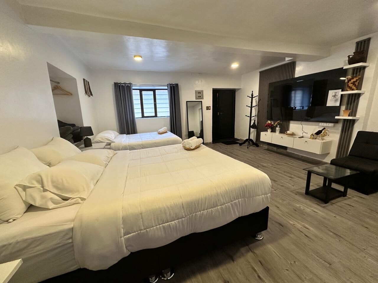 Ein Hotelzimmer mit zwei Betten, einem Fernseher, einem Sofa und einem kleinen Tisch.