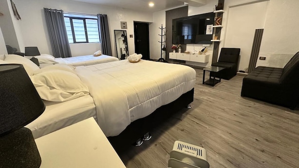 A modern hotel room with two beds, a desk, a chair, a TV, and a wardrobe. - ZEVEN HOUSE - CUSCO APARTMENT (Cusco)