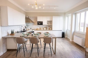 A modern kitchen with a central island, white cabinetry, and a dining area with four chairs.