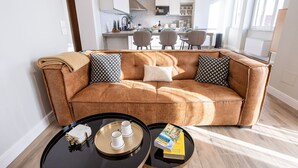 A modern living room with a brown leather sofa, two black and white patterned pillows, a black coffee table with a tray holding a white box, two cups, and a book. - Apartment in Cortona with 3 bedrooms sleeps 6 (Cortona)