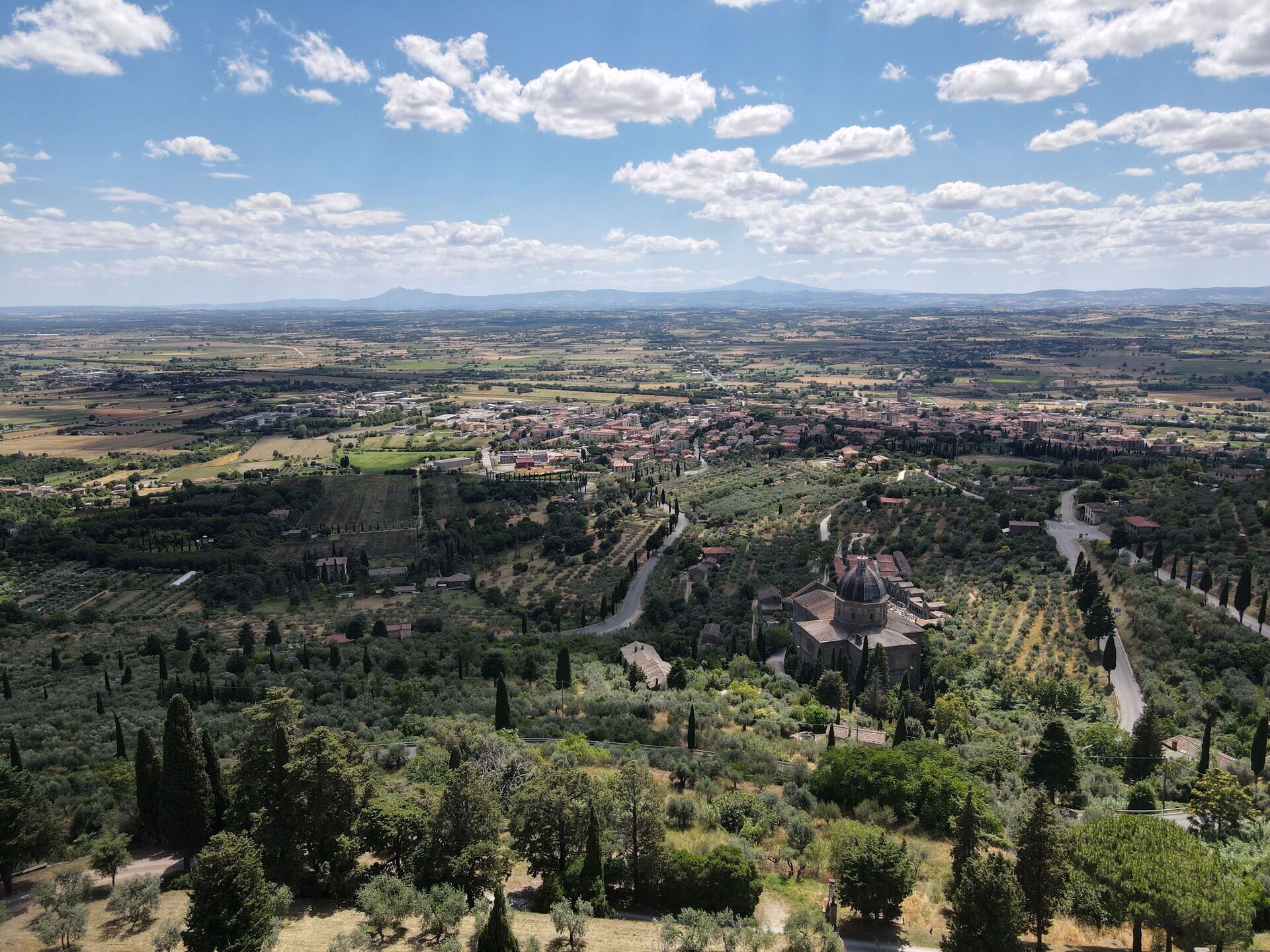 Une vue panoramique d’une ville avec une église imposante, entourée de verdure et sous un ciel dégagé.