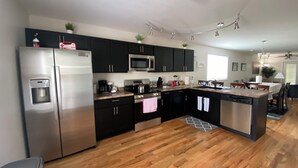 Una cocina moderna con armarios negros, electrodomésticos de acero inoxidable y suelo de madera.
