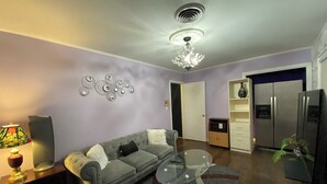 A living room with a sofa, a glass coffee table, a lamp, a decorative wall piece, and a refrigerator. - Elite Suite with private parking in North Jackson (Jackson)
