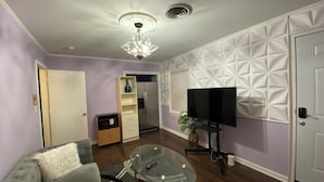 A living room with a glass coffee table, a sofa, a television, a microwave, and a refrigerator. - Elite Suite with private parking in North Jackson (Jackson)