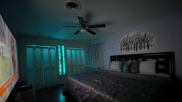 A dimly lit bedroom with a bed, a ceiling fan, and a wall-mounted artwork. - Elite Suite with private parking in North Jackson (Jackson)