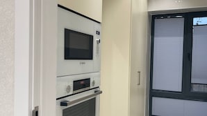 Une cuisine moderne équipée d’appareils électroménagers Bosch, notamment un four à micro-ondes, un four traditionnel et une horloge numérique.