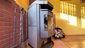A wood stove with a brick wall and a yellow wall in the background. - Holiday home in the Thuringian Forest (Langenbach)