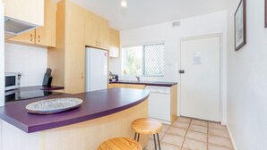 Een moderne keuken met houten kasten, een paars aanrecht, een magnetron en een spoelbak.