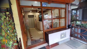 Entrada de um hotel com balcão de recepção, escada e vista do interior.