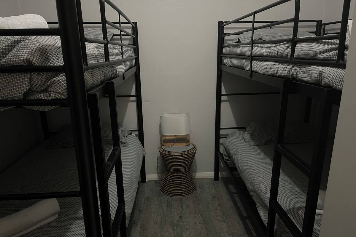 Une chambre avec un lit superposé, une petite table de chevet et une lampe.