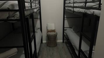 Habitación con literas, una mesita de noche pequeña y una lámpara.