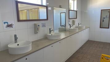 A public restroom with three sinks, hand dryers, and mirrors.