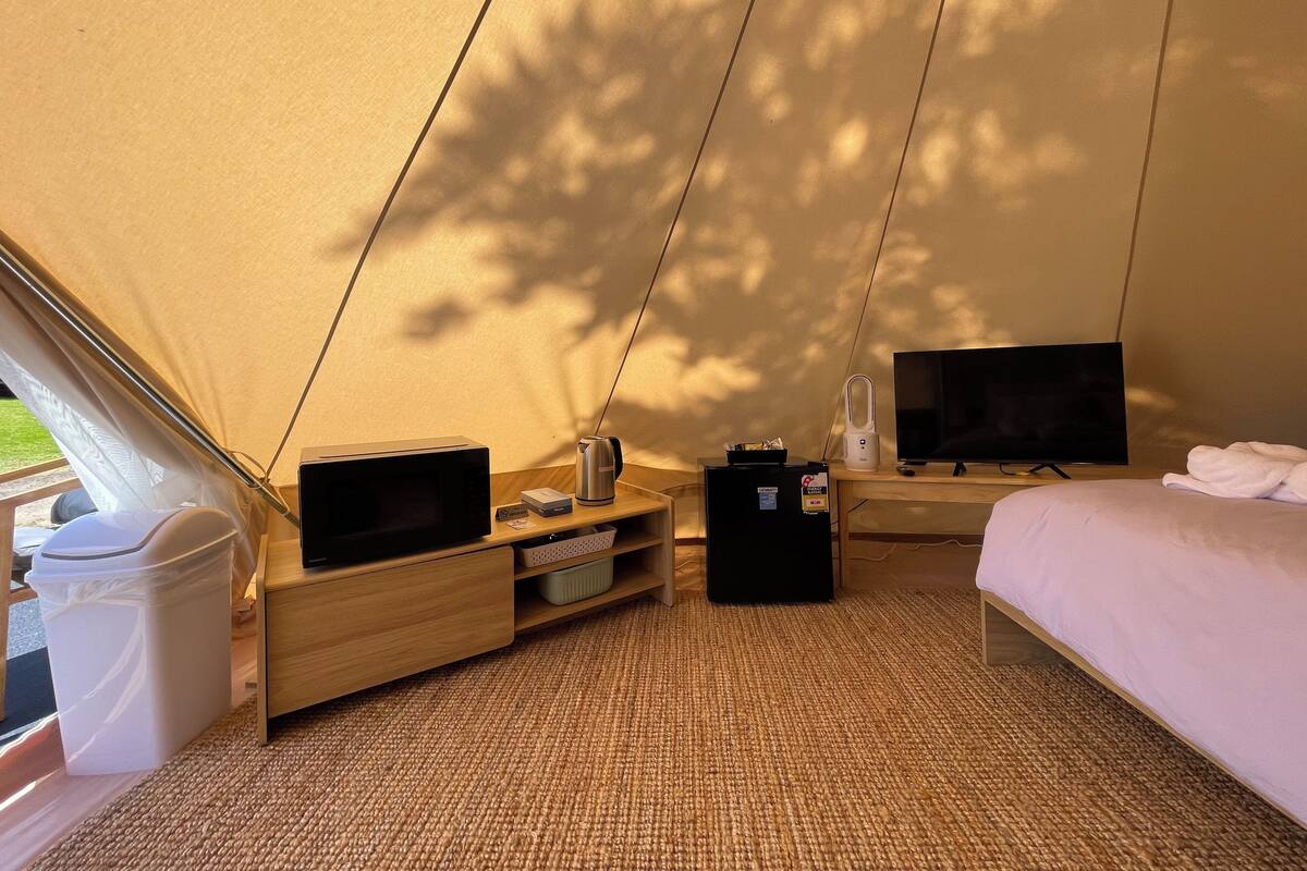 Une tente équipée d’un lit, d’une télévision, d’une bouilloire et d’un petit réfrigérateur.