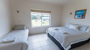 A hotel room with two beds, a large window, and a painting on the wall.