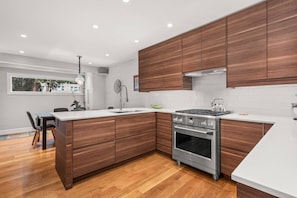 A modern kitchen with wooden cabinets, a stainless steel stove, and a white countertop.
