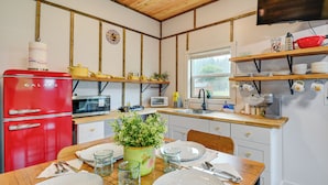 A kitchen with wooden beams, a red Galanz refrigerator, a microwave, a sink, and a dining table set with plates and cutlery. - Near ‘Twilight’ Sites & Scenic Hikes: Forks Apt (Forks)