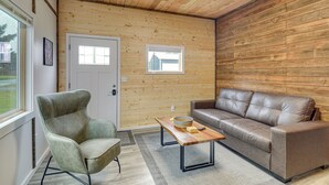 A room with a wooden ceiling, a brown leather sofa, a green armchair, and a wooden coffee table with a bowl and a book. - Near ‘Twilight’ Sites & Scenic Hikes: Forks Apt (Forks)