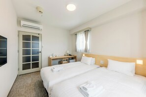 Une chambre d’hôtel avec deux lits, un bureau, une télévision et un appareil de climatisation.