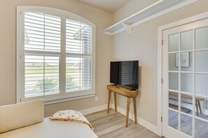 Ein Schlafzimmer mit einem Bett, einem Fernseher auf einem Schrank, einem Fenster mit Jalousien und einer Tür mit Glasfeldern.