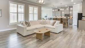 A spacious living room with a sectional sofa, a wooden coffee table, and a ceiling fan. - 8 Mi to Texas Tech: Spacious Lubbock Home (Lubbock)
