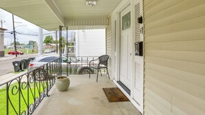 A covered porch with a metal railing, a potted plant, and a chair. - Work & Play: Colorful Home in Heart of NOLA! (New Orleans)