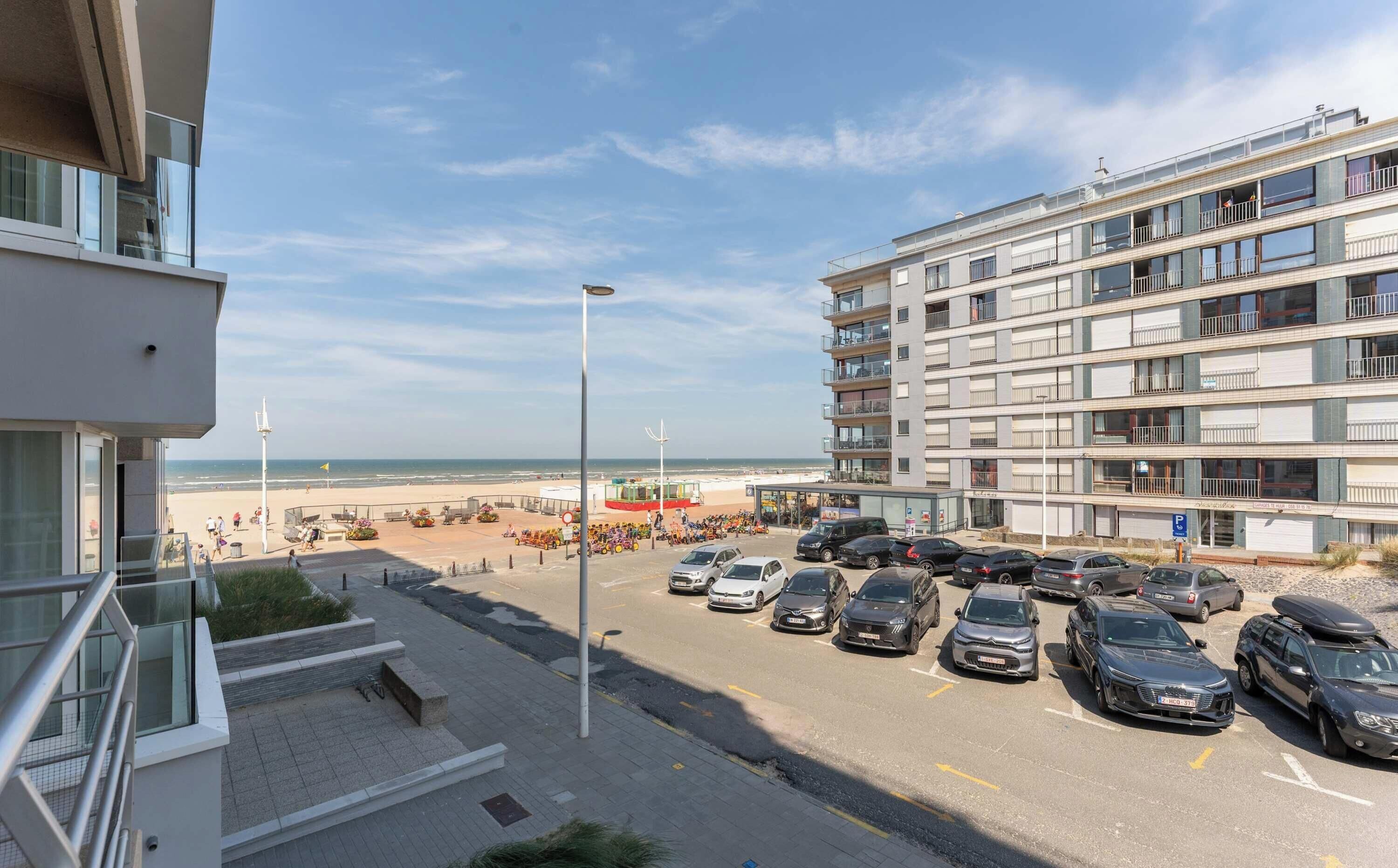 A multi-story building with balconies overlooking a beach.