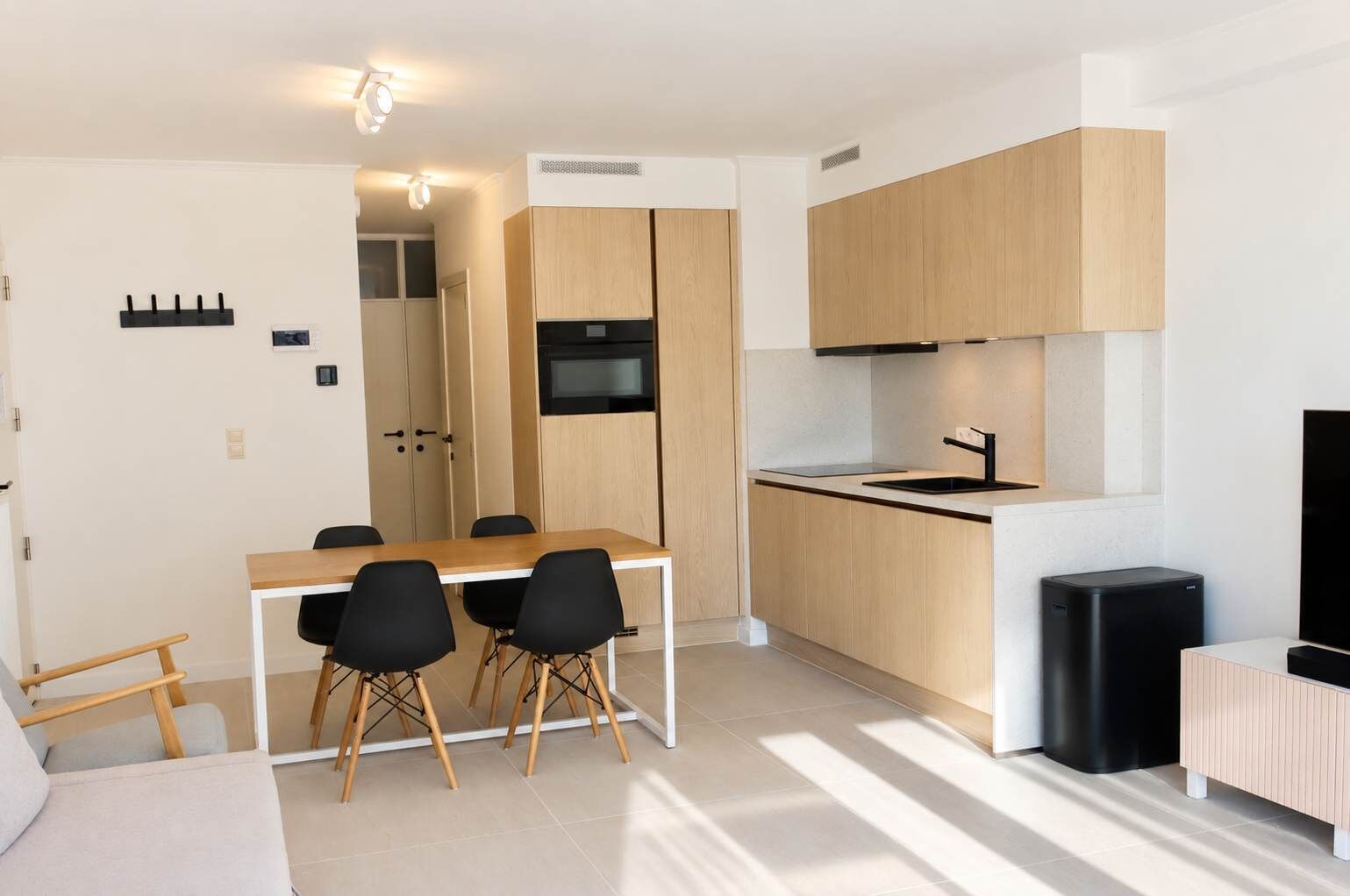 A modern kitchen with wooden cabinets, a built-in oven, and a black countertop.