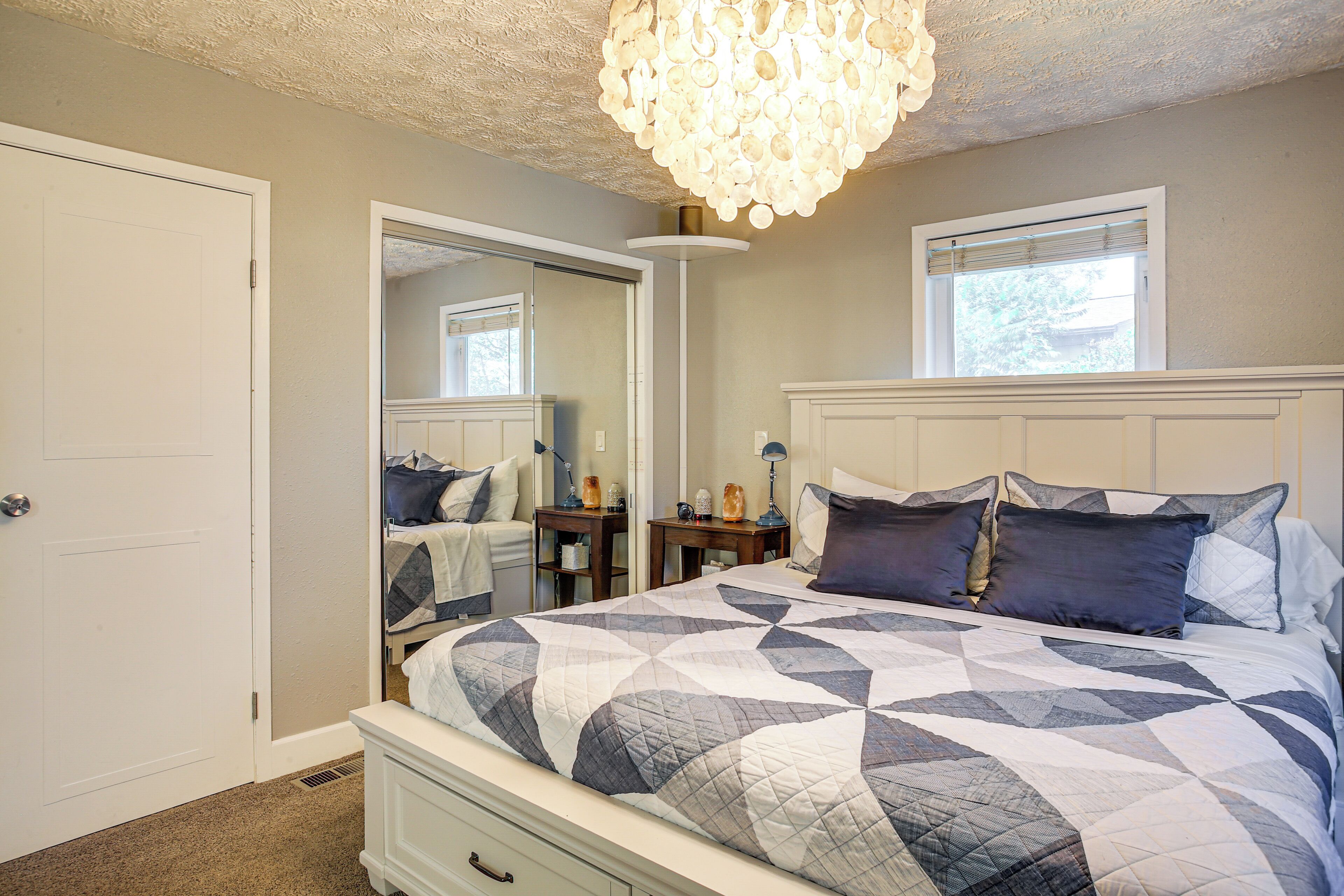 Une chambre à coucher avec un grand lit, une table de chevet, une commode, un miroir et un lustre.