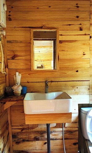 A wooden cabin bathroom with a white sink, a mirror, and a window. - To Chim Ri Homestay Mang Đen (Mang Den)