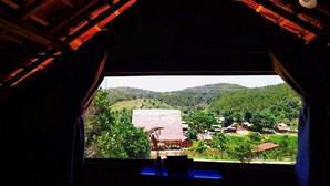 A view from a window with a wooden ceiling, overlooking a rural landscape with houses and greenery. - To Chim Ri Homestay Mang Đen (Mang Den)