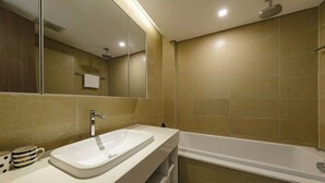 Een moderne badkamer met een witte wasbak, een grote spiegel en een bad.