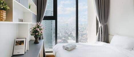 Un dormitorio moderno con un ventanal grande, una cama bien tendida y una estantería empotrada.