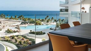 Un espace de restauration moderne offrant une vue sur une piscine et l’océan.