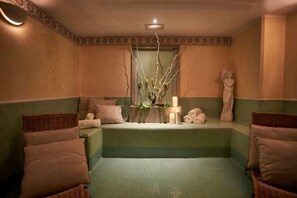 A spa room with a bathtub, a small table with a vase, and a statue. - Sina Bernini Bristol, Autograph Collection (Rome)
