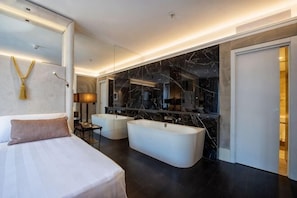 A modern hotel room with a large bed, a bathtub, and a marble wall. - Sina Bernini Bristol, Autograph Collection (Rome)