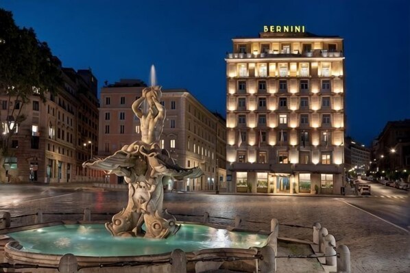 Une fontaine dans une place, avec un hôtel appelé « BERNINI » en arrière-plan.