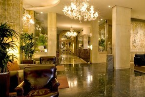 Eine Lobby mit Marmorboden, Ledersitzmöbeln und einem Kronleuchter.