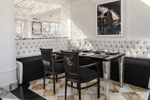 A dining area with a white cushioned bench, a round table, and black chairs. - Sina Bernini Bristol, Autograph Collection (Rome)