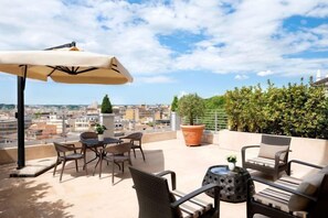 A rooftop terrace with outdoor furniture, a table, and a potted plant. - Sina Bernini Bristol, Autograph Collection (Rome)