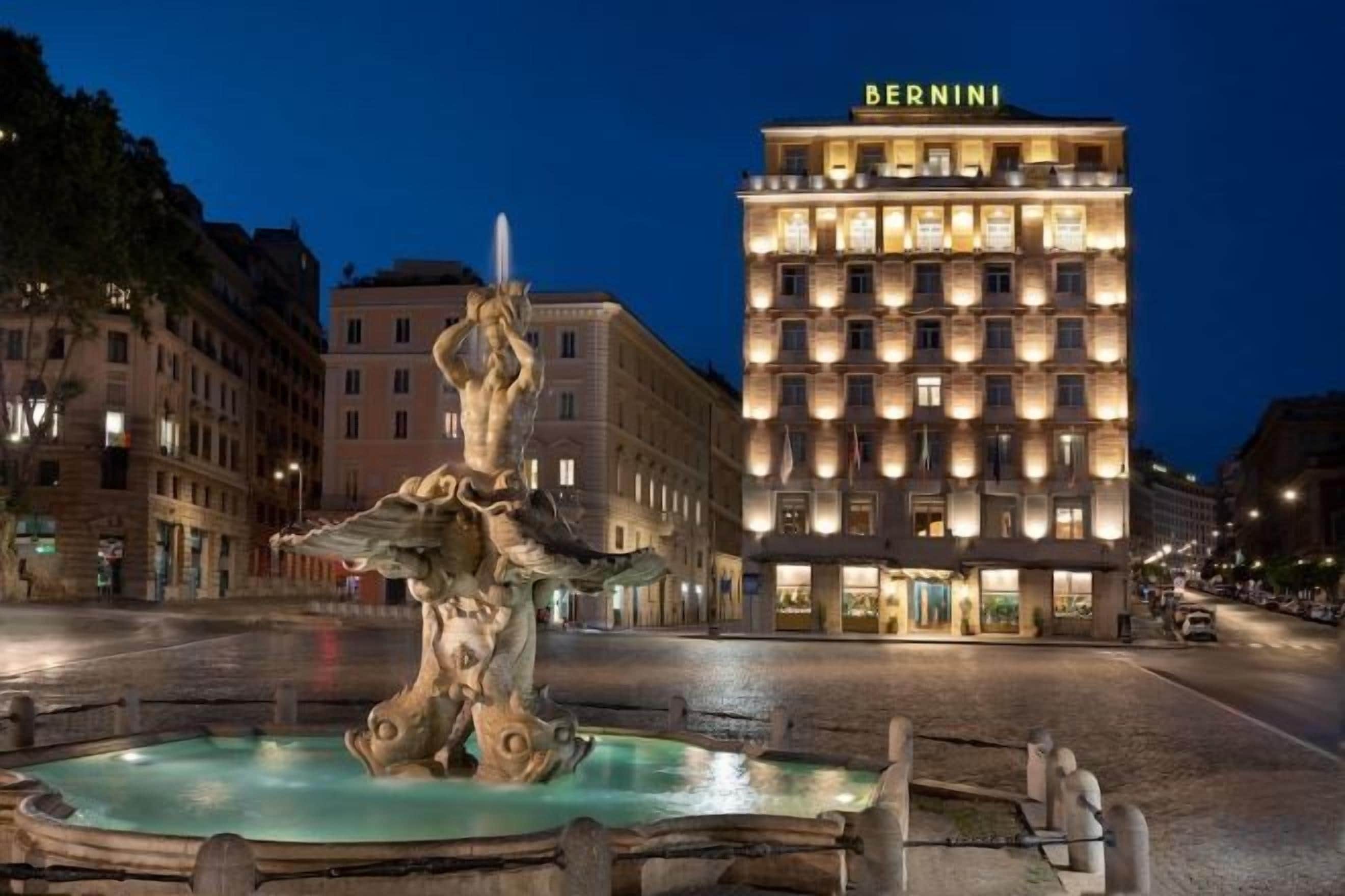 A fountain in a square with a hotel in the background.