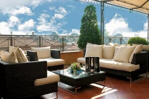 A rooftop terrace with outdoor furniture, a glass coffee table, and a view of the sky. - Sina Bernini Bristol, Autograph Collection (Rome)
