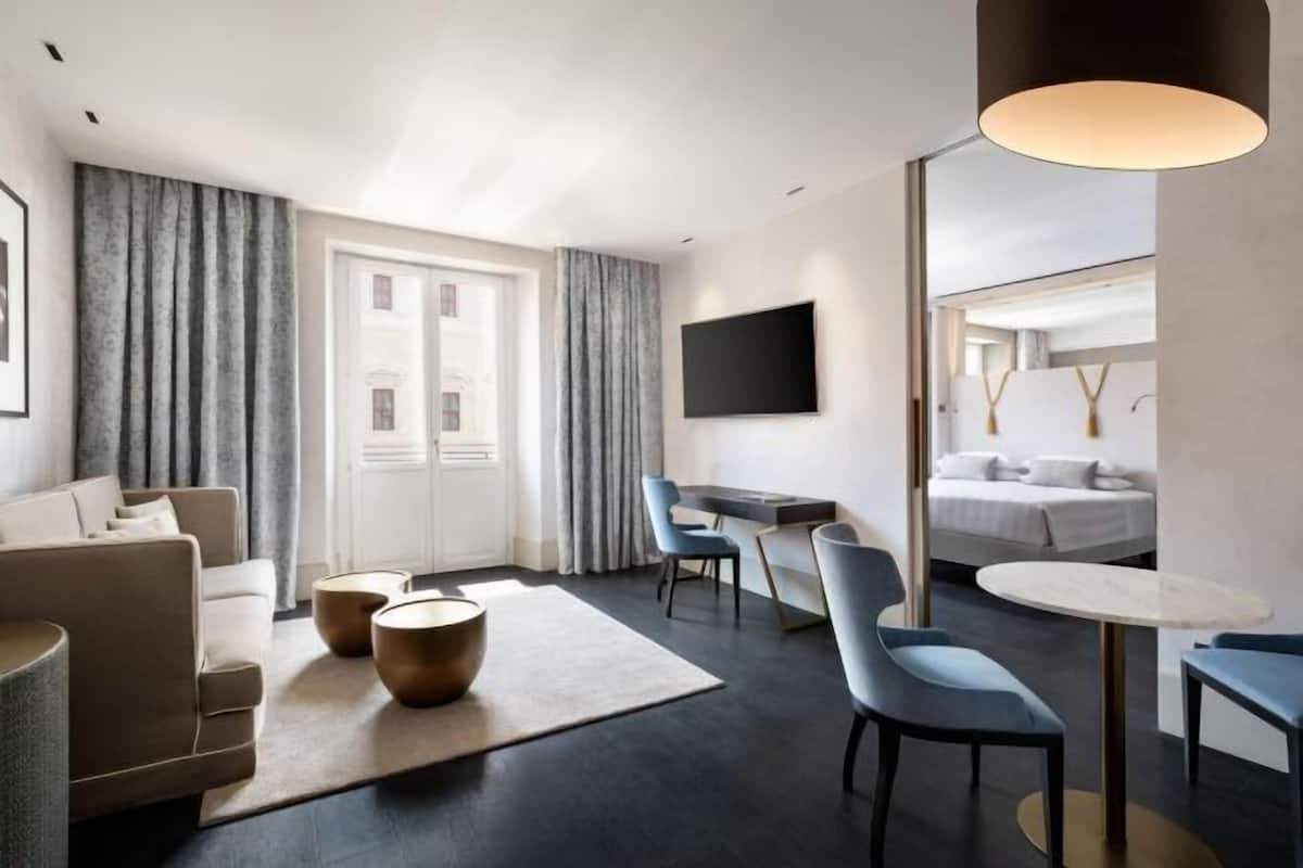 Moderni hotellihuone, jossa on sohva, työpöytä, sänky ja televisio.