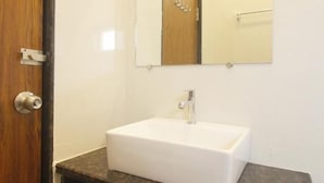 A bathroom with a sink, mirror, and a wooden countertop. - HOTEL MINT PARK (Balanagar)
