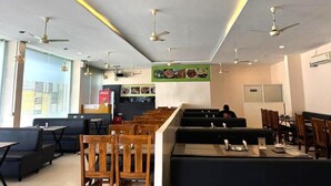 A restaurant with booths and tables, ceiling fans, and a menu board on the wall. - HOTEL MINT PARK (Balanagar)