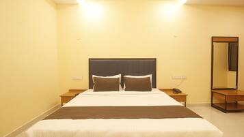 Una habitación de hotel con una cama grande, mesitas de noche, un espejo y un teléfono.